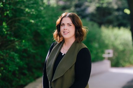 Woman smiling at camera in front of greenery