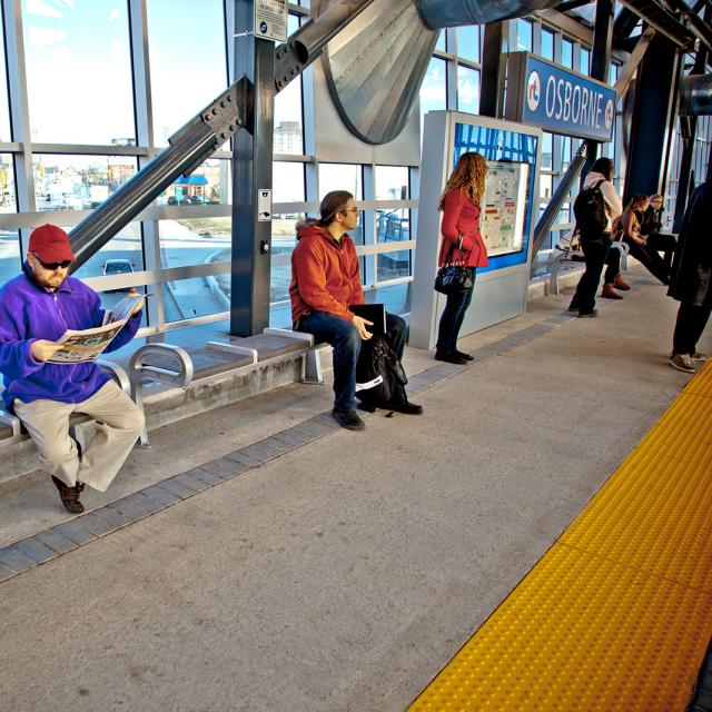 Osborne Bus Rapid Transit Station. Five people wait in the bus transit station for their bus.